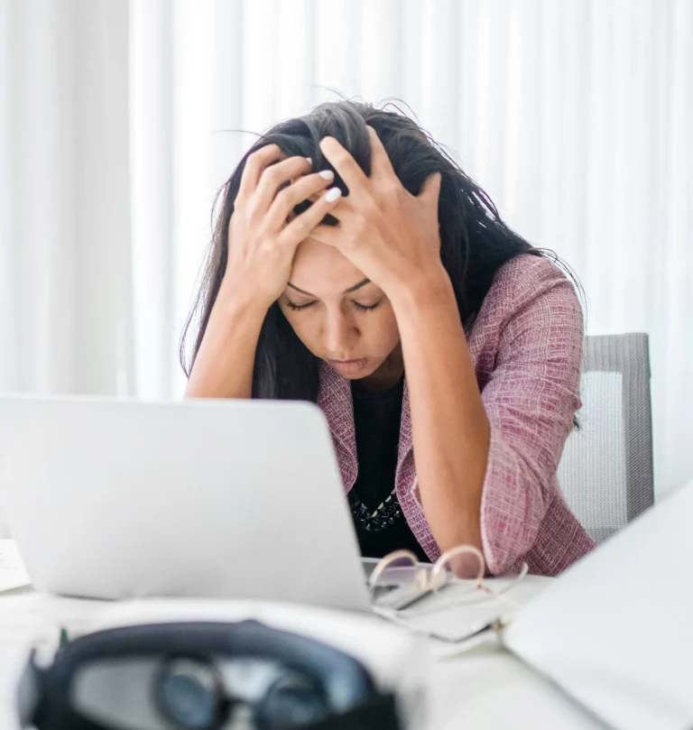 Tired and stessed woman sitting at the desk behind the laptop